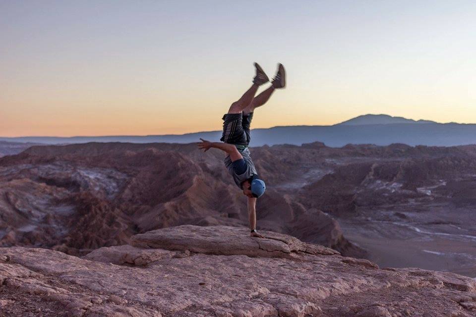 Colin doing a handstand on a cliff edge at sunset